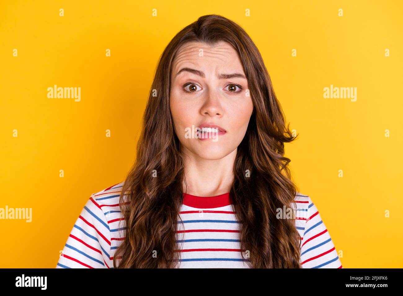 Foto von unsicher aufgeregt junge Dame gekleidet gestreiften T-Shirt beißen Lippe isoliert gelbe Farbe Hintergrund Stockfoto