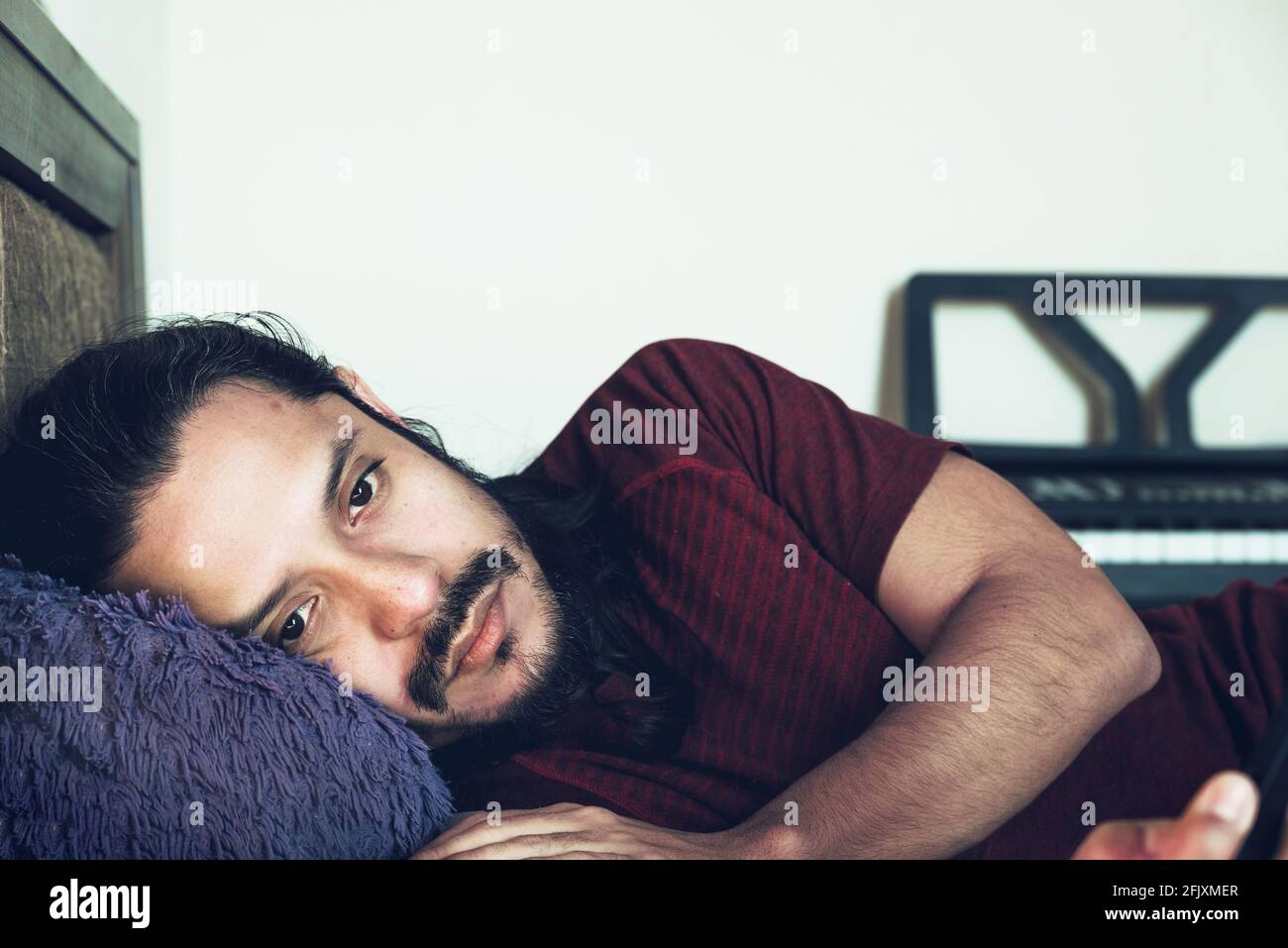 Junger trauriger lateinischer Mann, der zu Hause krank auf dem Bett lag Depression und Angst Stockfoto