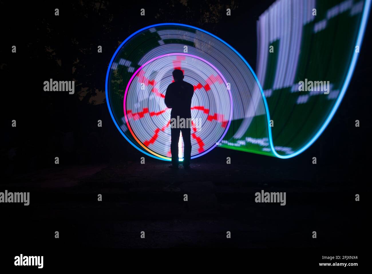 Eine Person steht allein gegen schöne Farbkreis LED-Licht Malen als Hintergrund Stockfoto