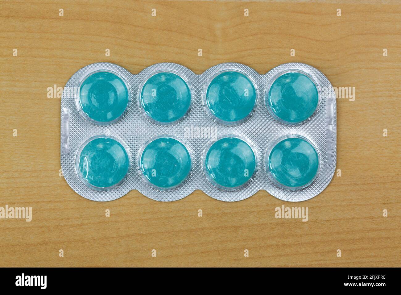 Blaue Lutschtabletten Medizin für schwere Halsschmerzen mit 2 antiseptischen Mitteln, Anästhetikum für effektive Schmerzlinderung, Draufsicht auf Holzhintergrund Stockfoto