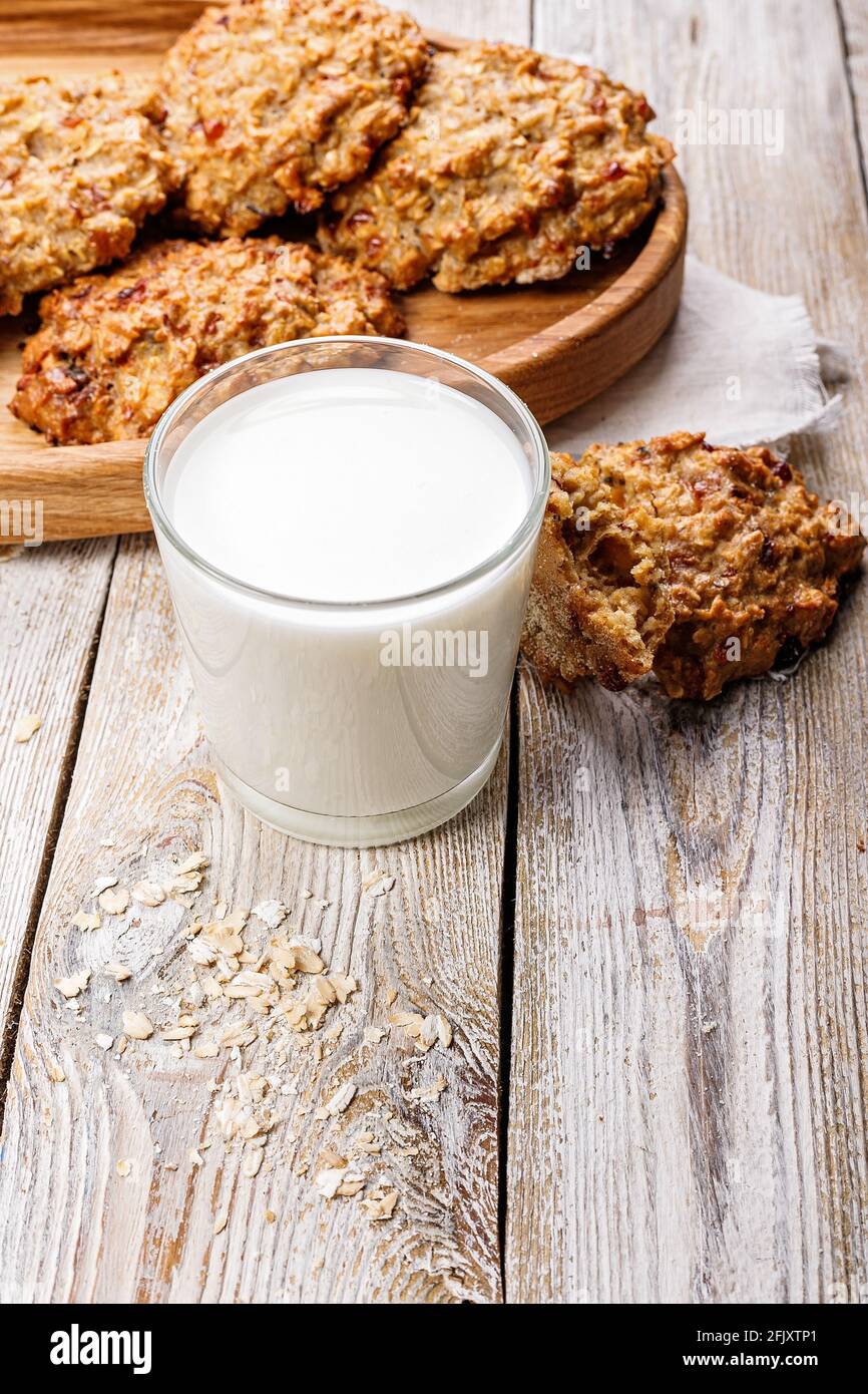 Hausgemachte Haferflocken-Kekse und Glasmilch. Hausgemachtes glutenfreies und zuckerfreies Rezept. Rustikaler Holzhintergrund und Leinenserviette. Lecker und gesund süß Stockfoto