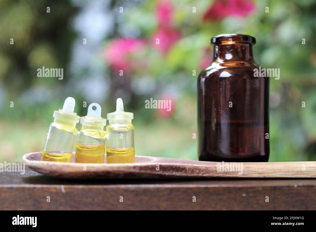 Cannabisöl, CBD-Öl, Cannabisextrakt in 3 winzigen Behältern auf einem Holzlöffel. Unscharfer Hintergrund in der Natur. Medizinische und Freizeitkonsum, Marihuana Stockfoto