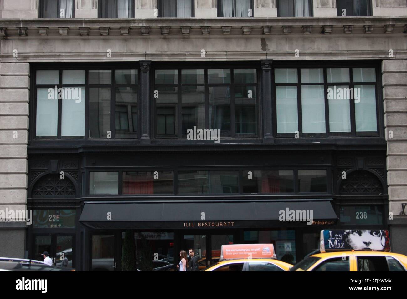 Das Ilili Restaurant ein libanesisches mediterranes Restaurant in New York City. Taxis fahren vorbei, eines mit einer „Les miserable“-Werbung Stockfoto