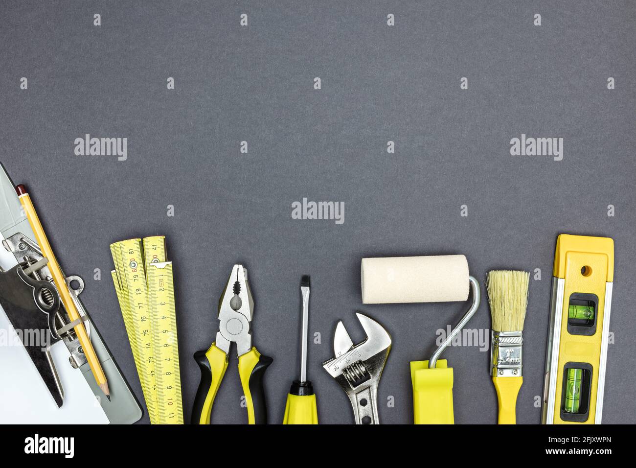 Anstrich- und Reparaturwerkzeuge für Hausrenovierungsarbeiten. Verschiedene Arten von Werkzeugen auf grauem Hintergrund. Stockfoto