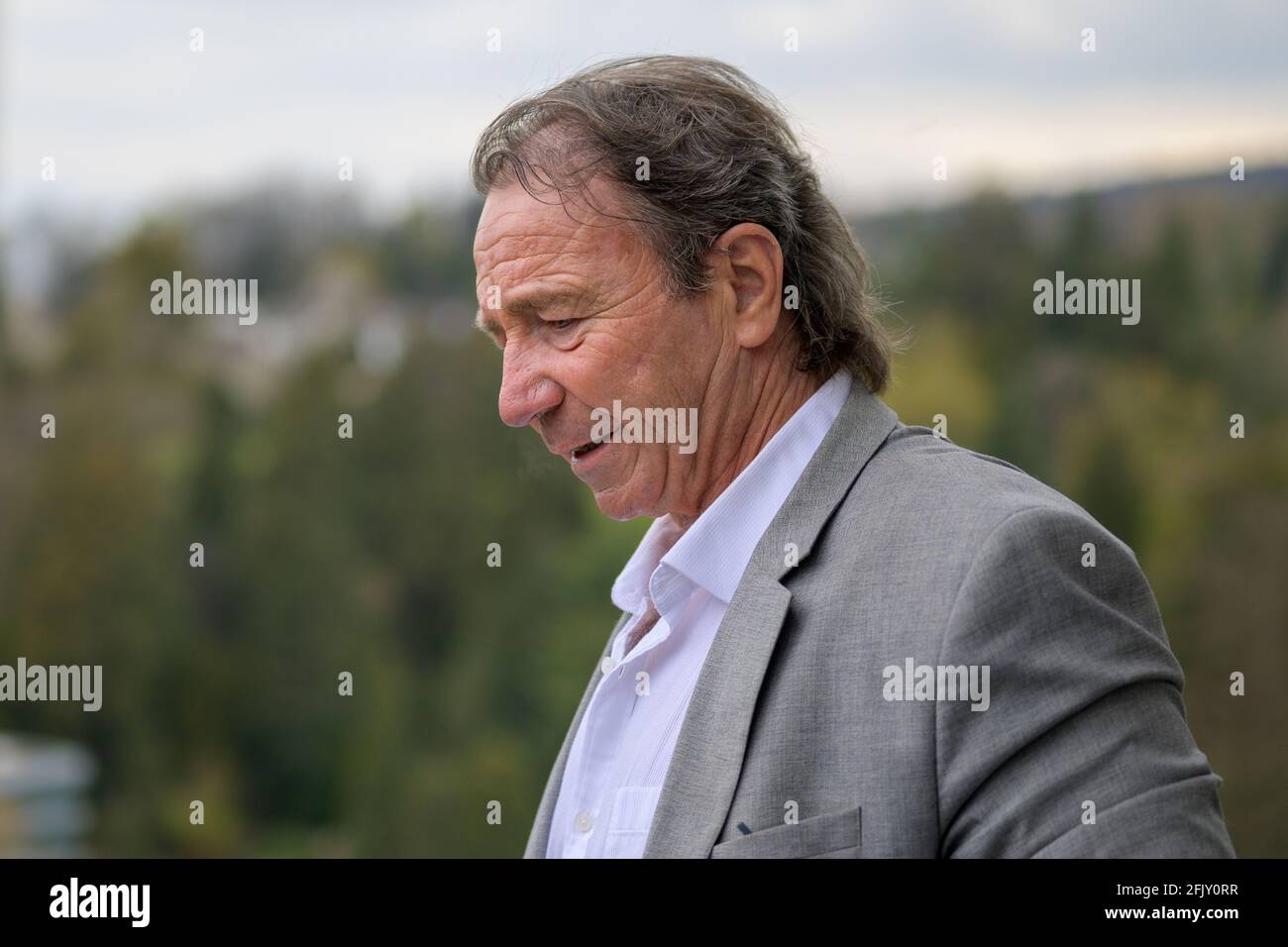 Nachdenklicher Geschäftsmann mittleren Alters, der mit einem auf den Boden blickt Kontemplativer Ausdruck in einem Profilportrait im Freien gegen ein ländliches Hintergrund Stockfoto