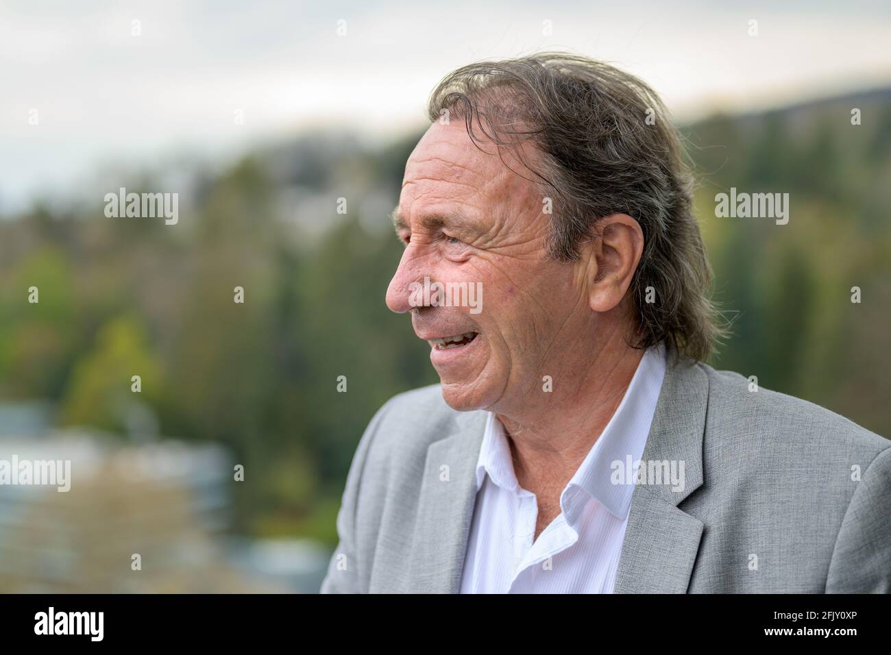 Nachdenklicher Geschäftsmann mittleren Alters, der mit einem besinnlichen Ausdruck in aufschaut Ein Porträt im Freien vor ländlicher Kulisse Stockfoto