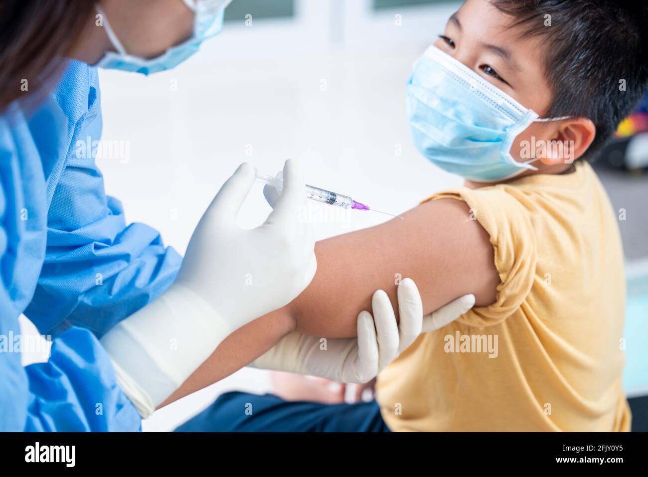 Arzt, der eine Impfung in der Schulter des Patienten Junge oder Kind Person und glücklich, Injektion am Arm, Coronavirus, covid-19 Impfstoffkrankheit Vorbereitung Stockfoto