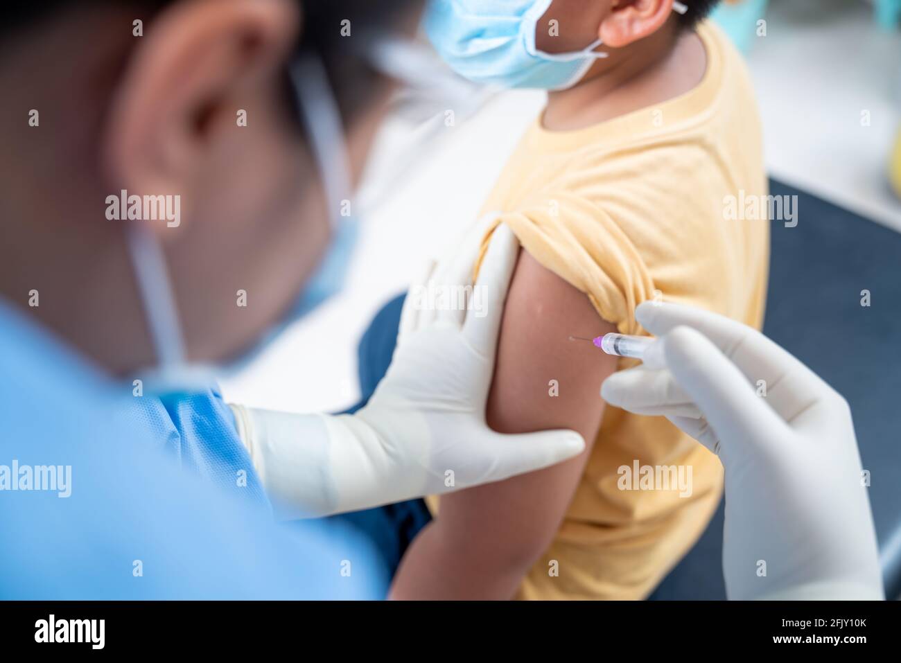 Nahaufnahme Arzt, der eine Impfung in der Schulter des Patienten Jungen oder Kind Person, Coronavirus, covid-19-Impfstoff-Krankheit Vorbereitung für den menschlichen klinischen Stockfoto