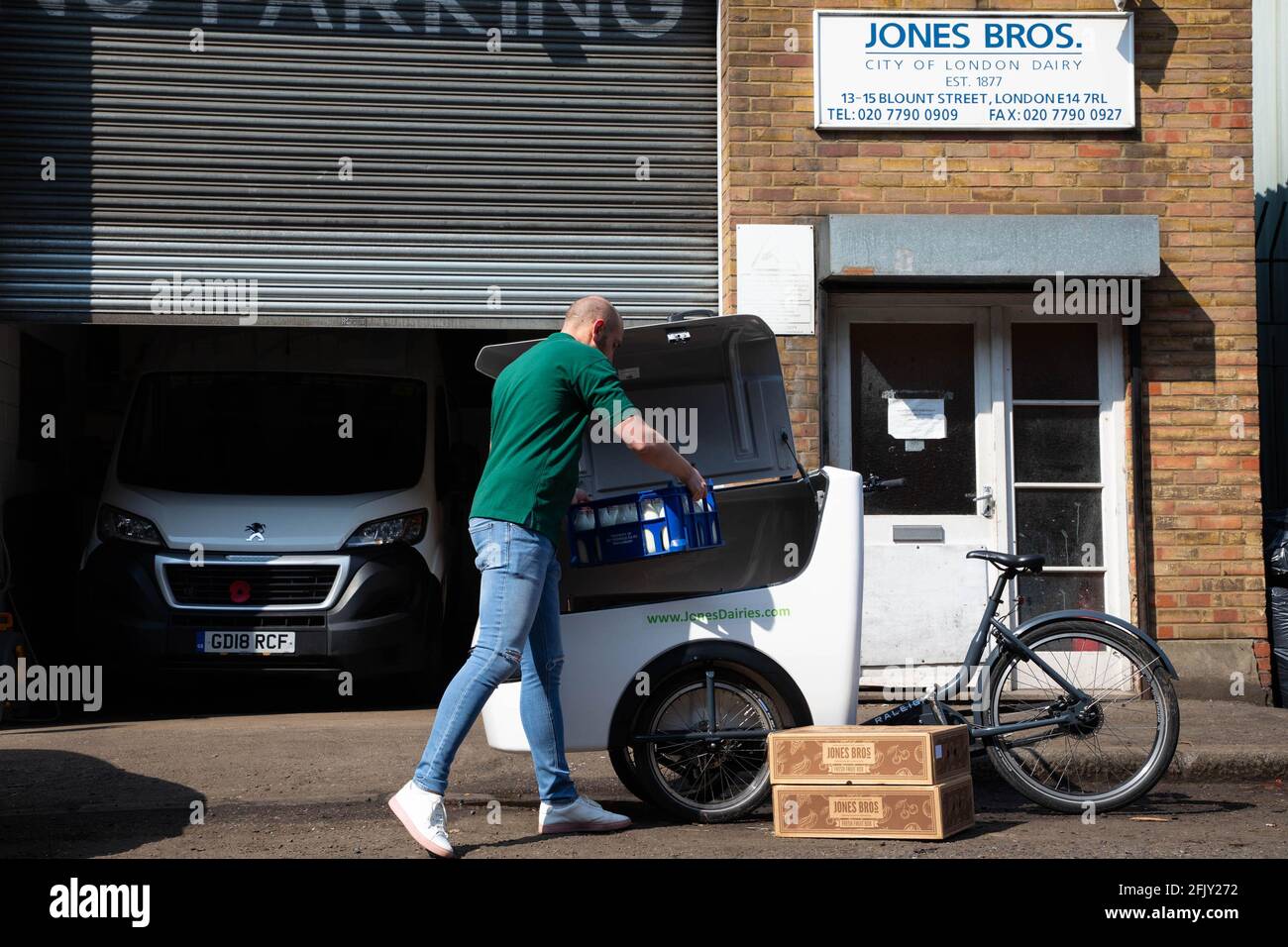 REDAKTIONELLE VERWENDUNG NUR Henry Jones von Jones Bros Dairy lädt Milch in ein E-Cargo-Fahrrad von Raleigh, da die Molkerei die Rückgabe des Fahrrads auf ihrer täglichen 10-Meilen-Lieferroute in London ankündigt, um die Emissionen zu reduzieren. Ausgabedatum: Dienstag, 27. April 2021. Stockfoto