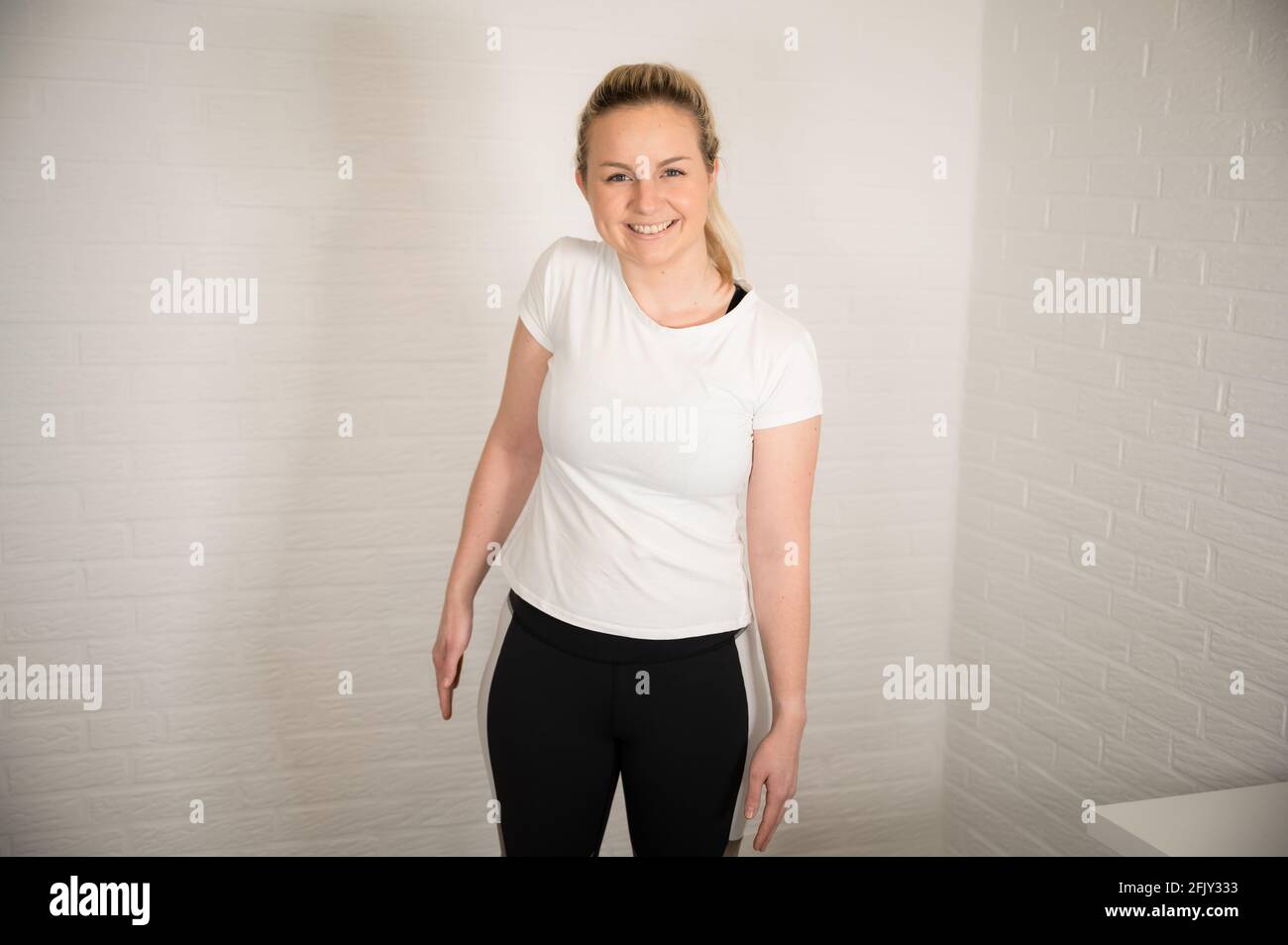 Glückliche blonde Frau macht Fitness-Übung mit Wasserflaschen - Basic Sport Workout als Training zu Hause Stockfoto