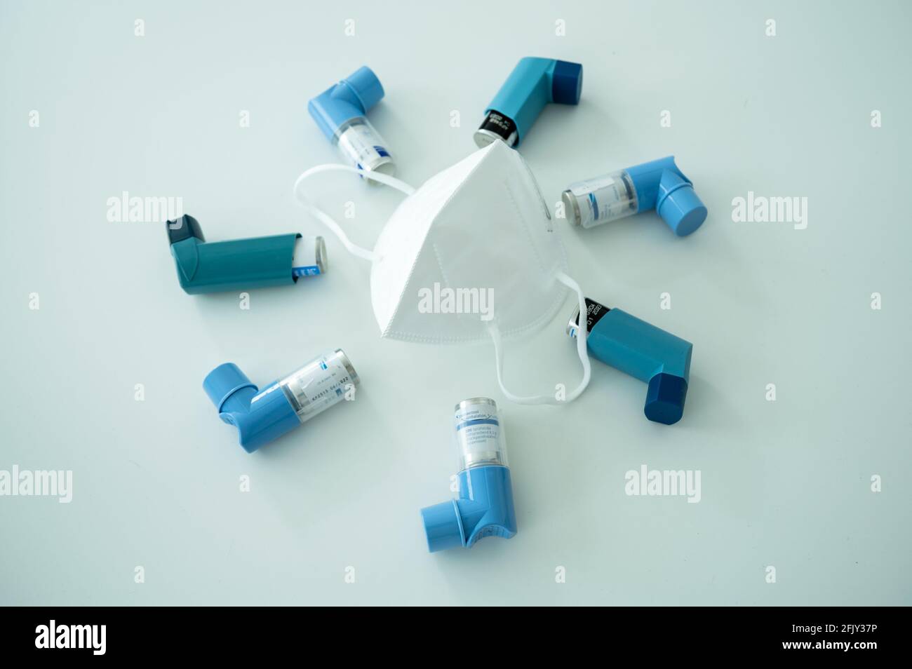 Verschiedene Asthmaspray-Inhalatoren und eine Covid-19 Atemschutzmaske auf Eine weiße Oberfläche Stockfoto