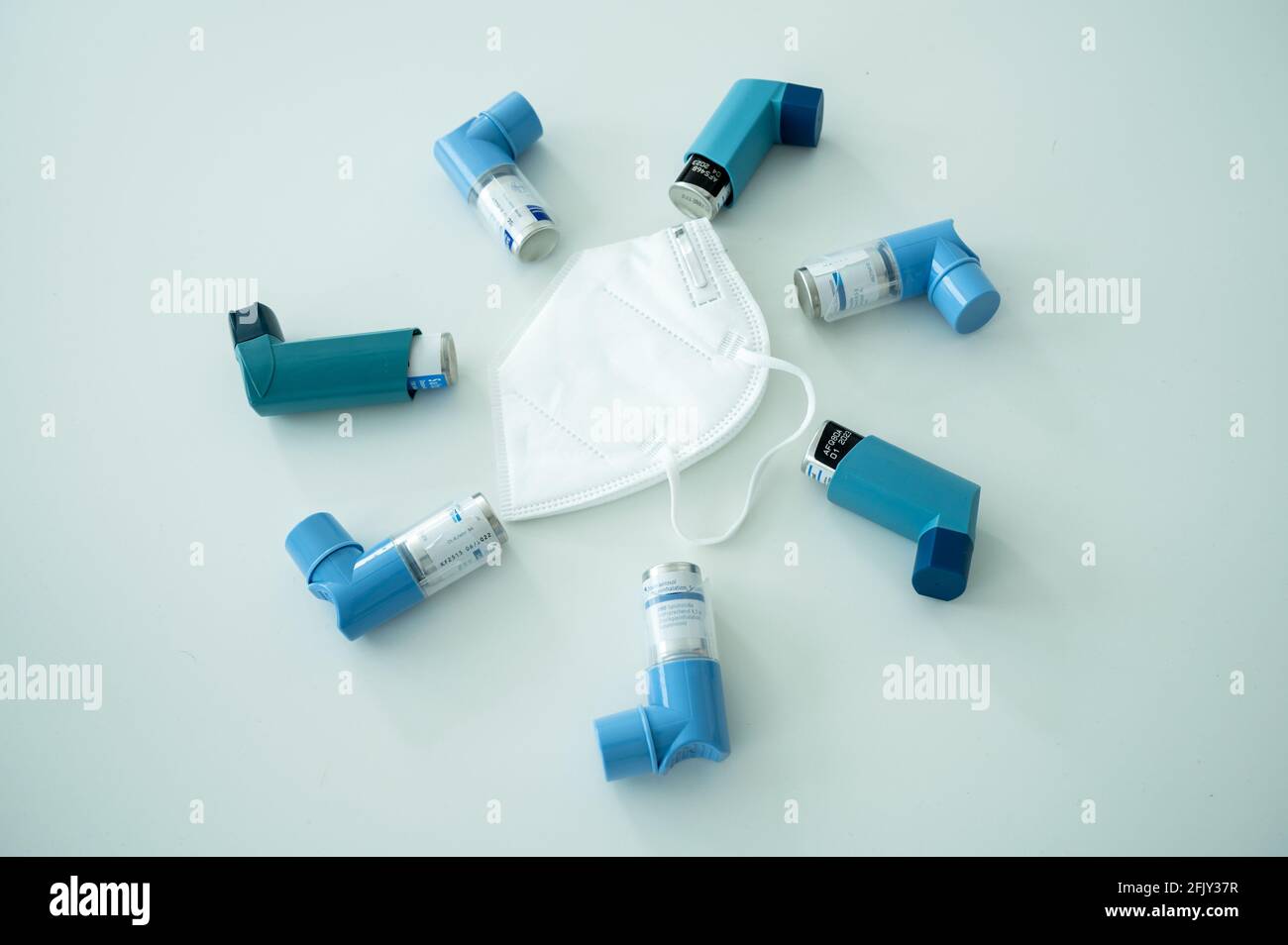 Verschiedene Asthmaspray-Inhalatoren und eine Covid-19 Atemschutzmaske auf Eine weiße Oberfläche Stockfoto