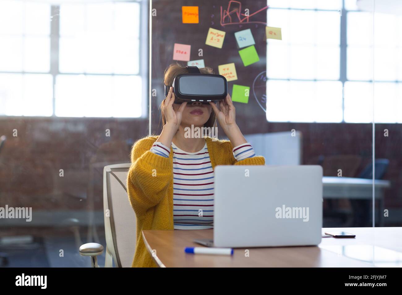 Porträt einer asiatischen Geschäftsfrau, die vor einem Laptop sitzt Virtual Reality-Headset Stockfoto