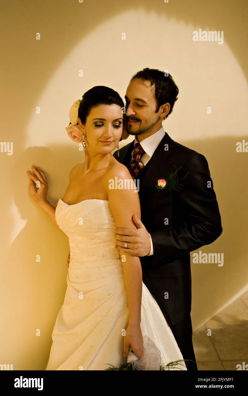 Wunderschönes Brautpaar (Braut und Bräutigam), das vor einer weißen Wand posiert. Stockfoto