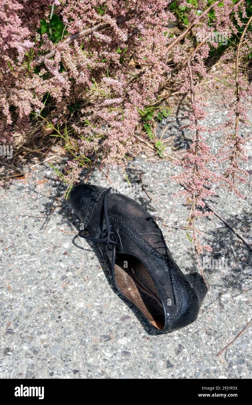 Femininer schwarzer Schuh, der in Italien auf dem Bürgersteig aufgegeben wurde Stockfoto