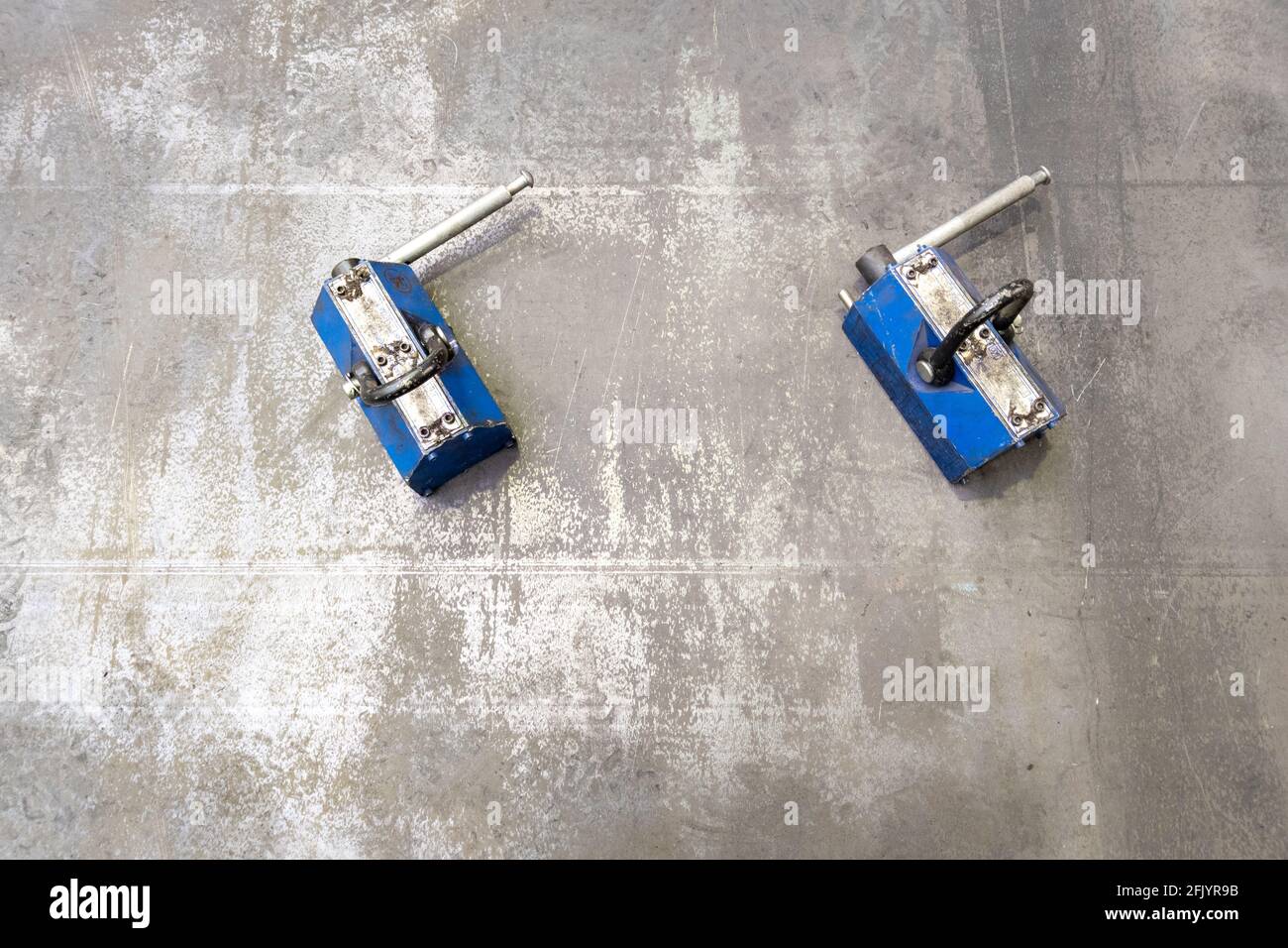 Blaues Paar Industriemagnete auf flacher Blechoberfläche. Stockfoto Blaues Paar Industriemagnete auf flacher Blechoberfläche. Stockfoto