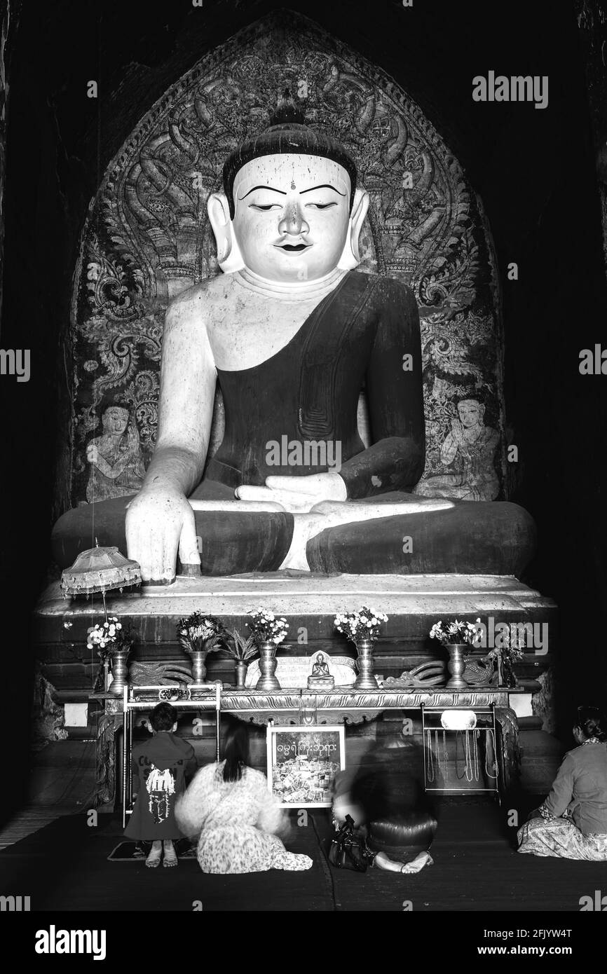 Frauen, die an EINER großen Buddha-Statue im Dhammayangyi Tempel, Bagan, Mandalay Region, Myanmar beten. Stockfoto