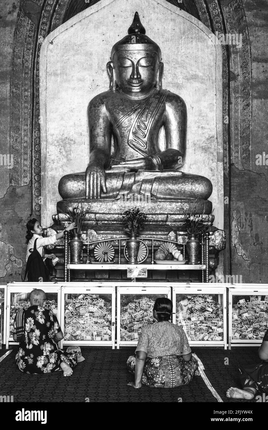 Frauen, die an EINER großen Buddha-Statue im Dhammayangyi Tempel, Bagan, Mandalay Region, Myanmar beten. Stockfoto