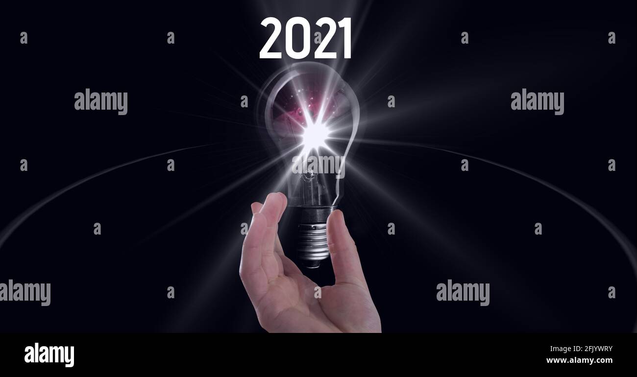Zusammensetzung von 2021 mit Hand halten beleuchtete Glühbirne an Schwarzer Hintergrund Stockfoto
