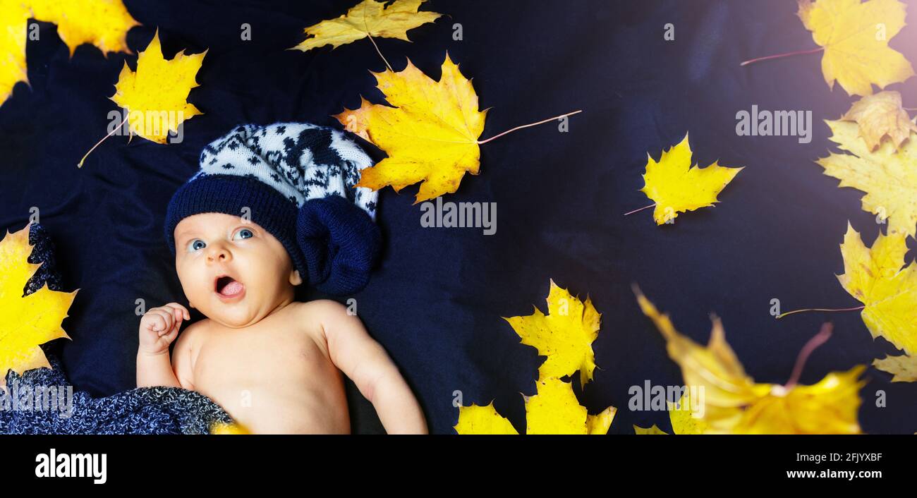 Neugeborenes Baby mit Herbstblättern in warmem Hut Stockfoto