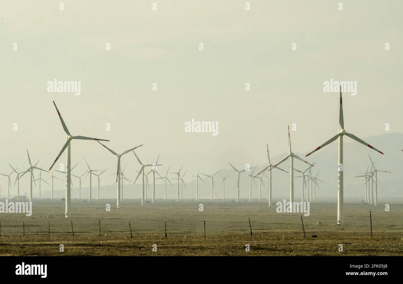 Windturbinen und Stromleitungen durchziehen die Wüste am westlichen Stadtrand von Turpan, an einem der heißesten Orte der Welt. Erneuerbare Energie aus Wind wird von den Chinesen zunehmend zum Ausbau ihrer stromhungrigen Industrien genutzt, wie hier in OstXinjiang, China, VR China, zu sehen ist. © Time-Snaps Stockfoto