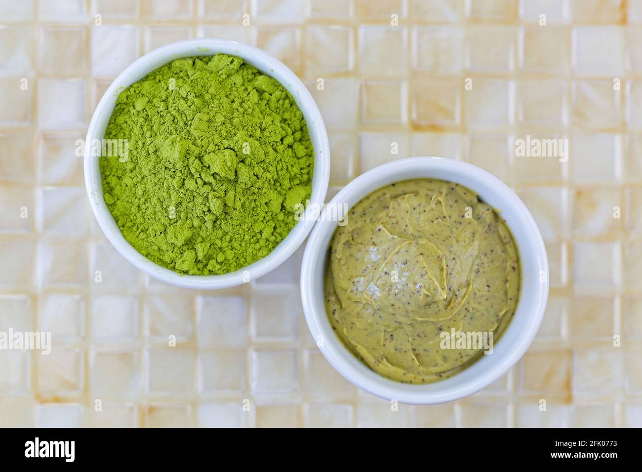 Feingemahlenes japanisches Matcha-Grünteeblätterpulver neben grünem Teespeeling mit Walnussschale und Kakao-Peeling, Draufsicht Stockfoto