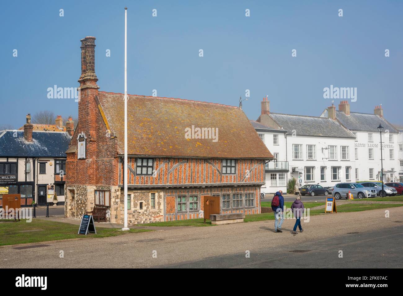 Aldeburgh Suffolk, Blick auf Menschen, die an der Moot Hall aus dem 16. Jahrhundert, dem heutigen Stadtmuseum, entlang der Strandpromenade in Aldeburgh, Suffolk, England, spazieren gehen Stockfoto