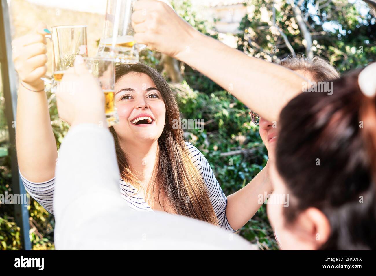 Eine Gruppe von Leuten, die im Freien fröhlich lächelnd Bier toasten Stockfoto