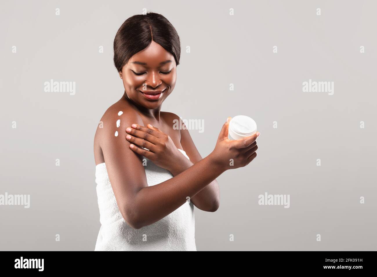 Konzept Der Körperpflege. Junge Afrikanische Frau, Die Feuchtigkeitsspendende Lotion Nach Dem Bad Auf Die Haut Auftragen, Schöne Schwarze Dame, Die Drei Punkte Pflegende Creme Ap Hat Stockfoto