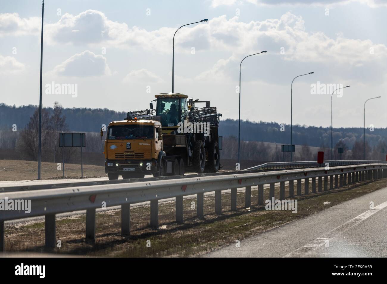 Interstate Highway Ufa - Kazan M7, Russland - 23. April 2021. KAMAZ Truck transportiert einen Mähdrescher zur Ernte auf dem Feld Stockfoto