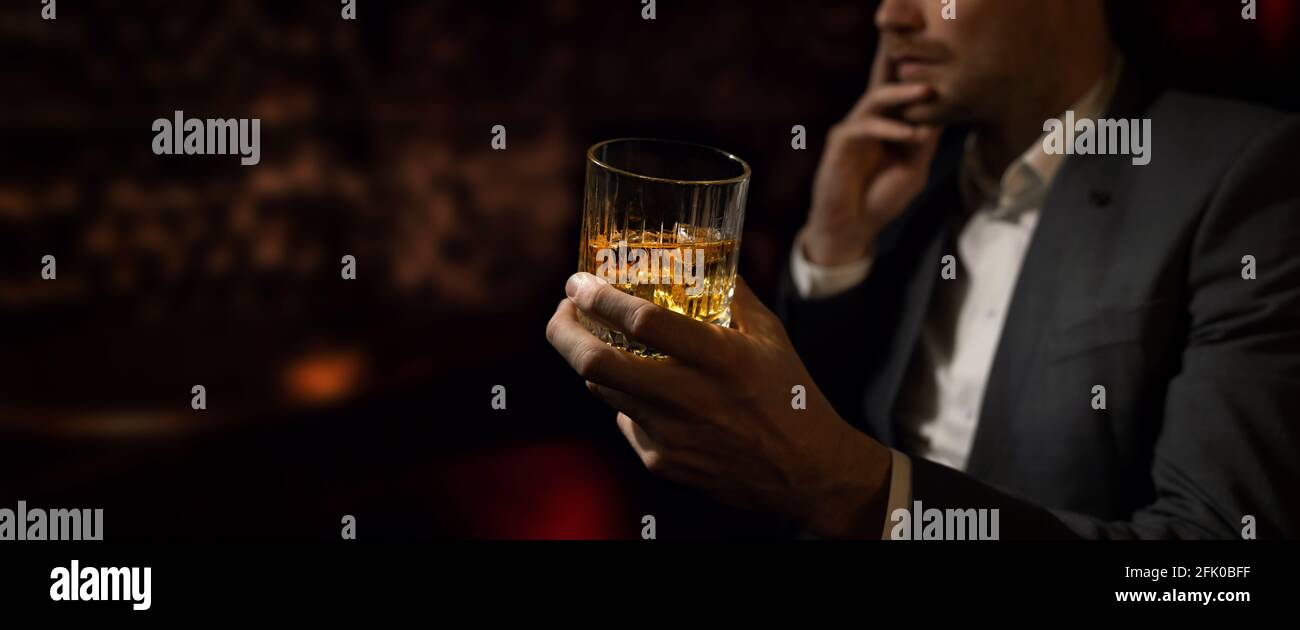 Mann in Anzug sitzt in der Luxusbar im Gentlemen Club und trinkt Whiskey. Copy Space Stockfoto