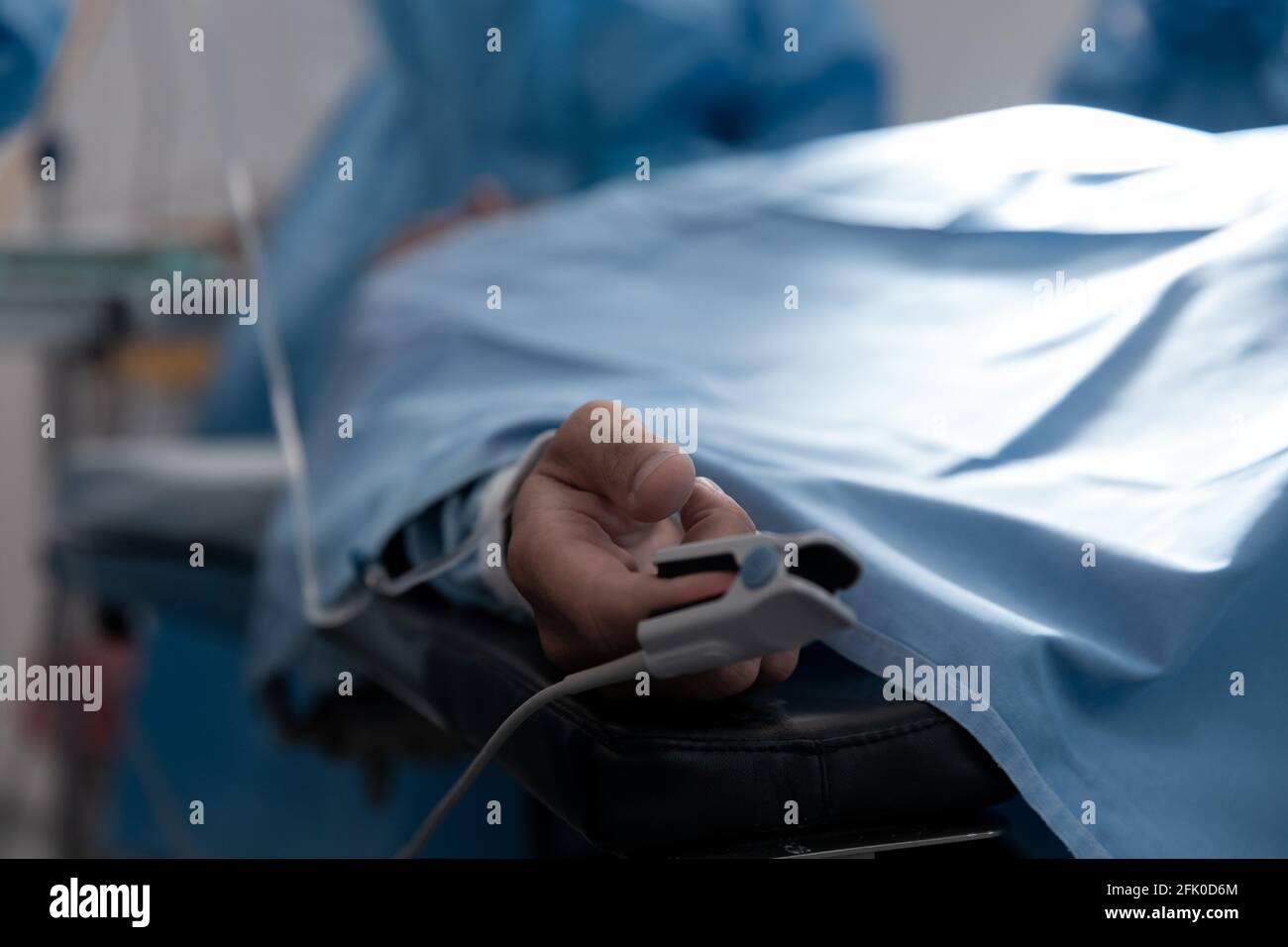 Patient, der auf dem OP-Bett liegt und ein Pulsoximeter mit der Fingerspitze trägt Operationssaal Stockfoto