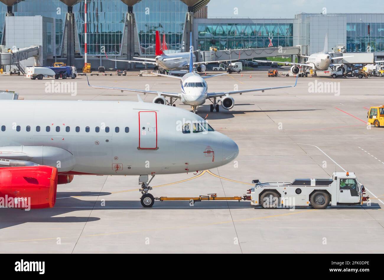 Schieben Sie zurück Abschleppwagen Flugzeug am Flughafen, Flughafen-Terminal Blick andere Flugzeuge, typische Luftfahrt Leben Arbeit Stockfoto