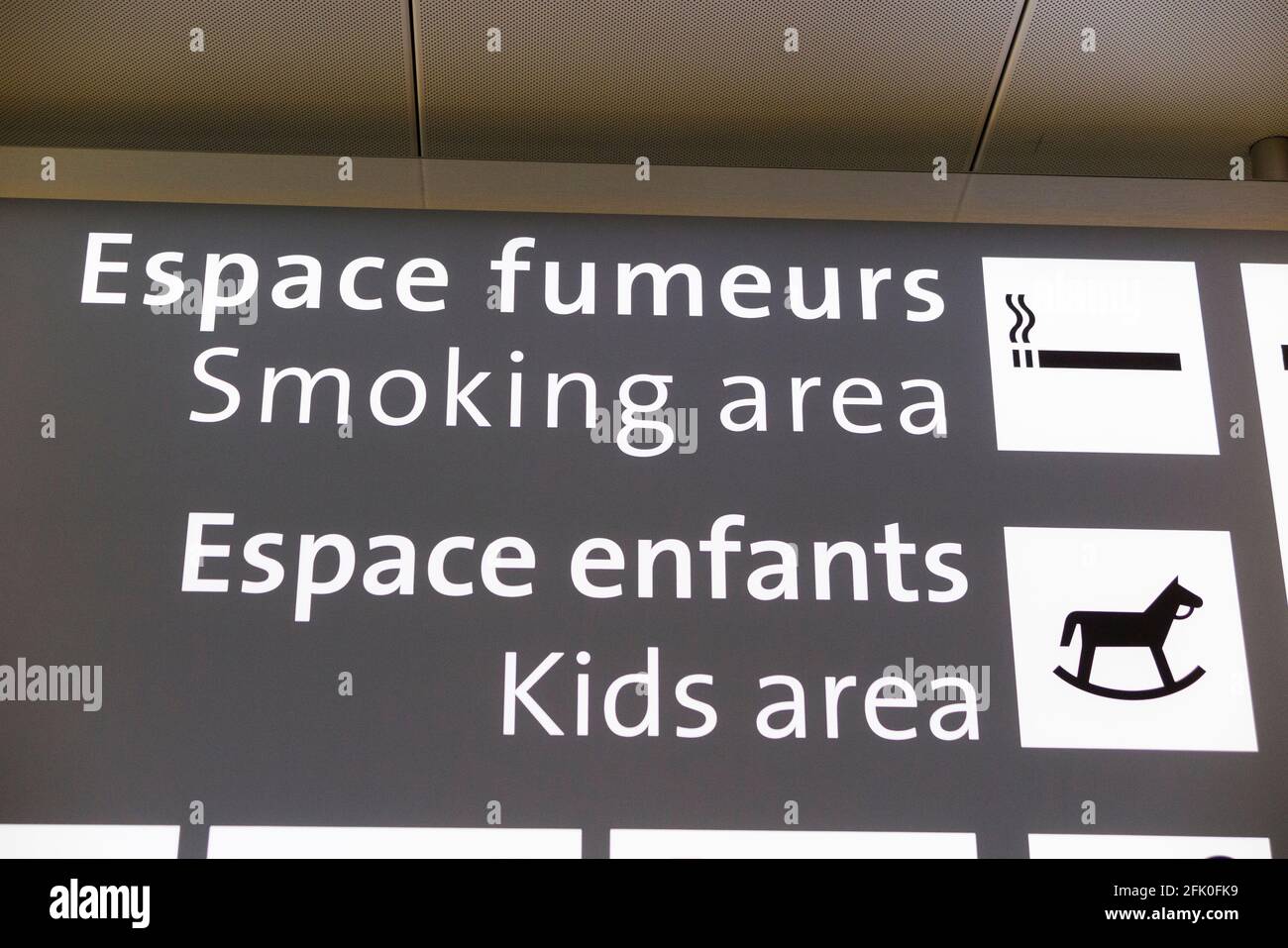 Schild/Bildschirm mit der Angabe des Spielbereichs für Kinder/Kinder und der Raucherzone in der Abflughalle des Flughafens Genf/Genf, Cointrin, Schweiz. (101) Stockfoto