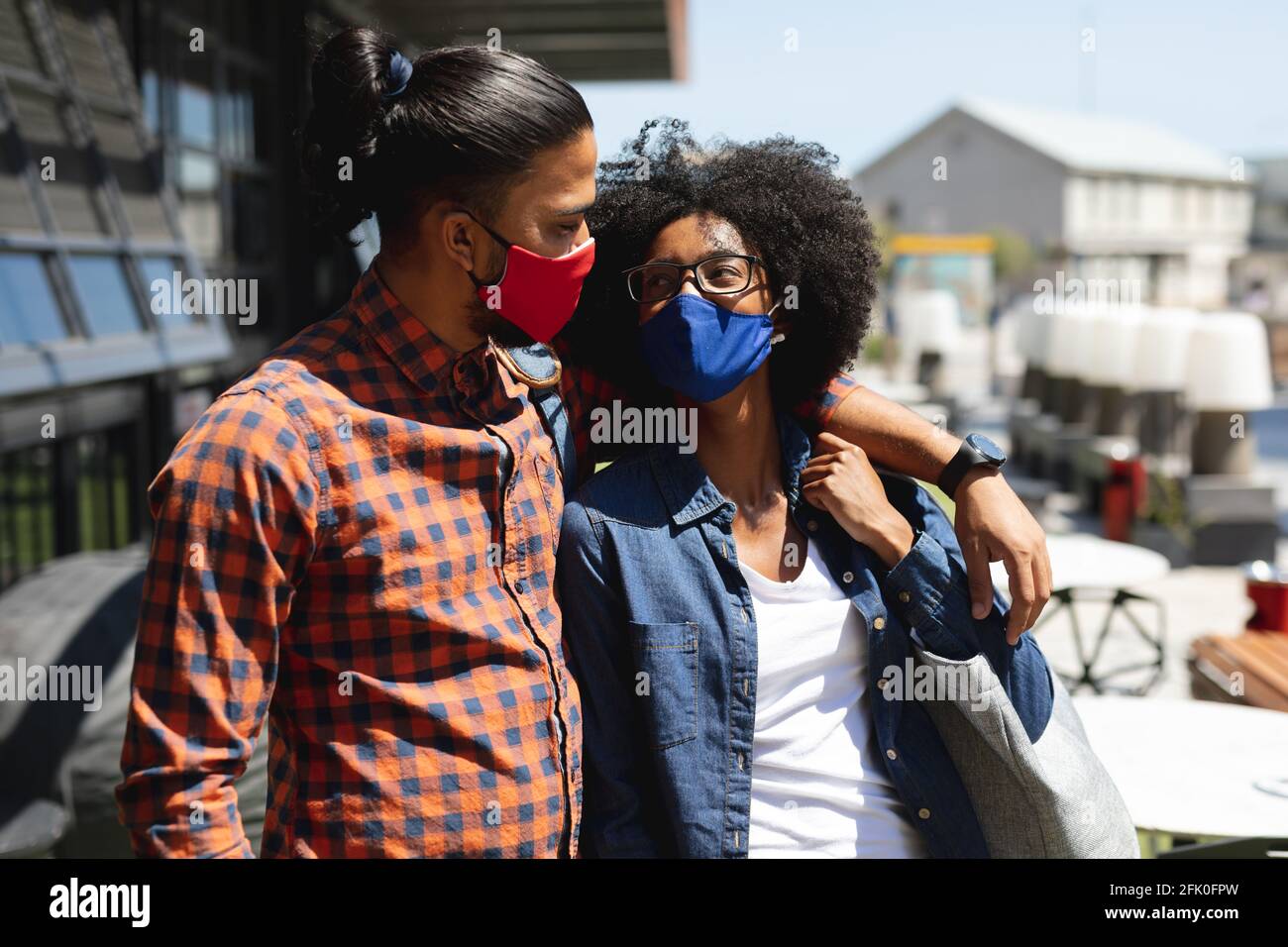 Mann mit gemischter Rasse und afroamerikanische Frau in Masken, umarmt Stockfoto