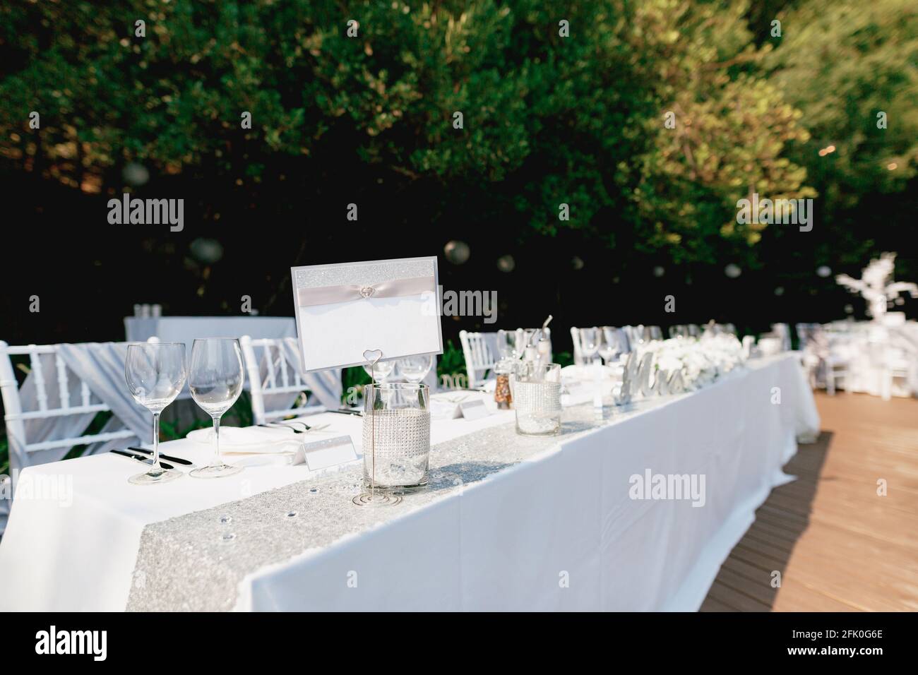 Ein leeres Schild steht auf einem wunderschön servierten Tisch Mit einer weißen Tischdecke Stockfoto