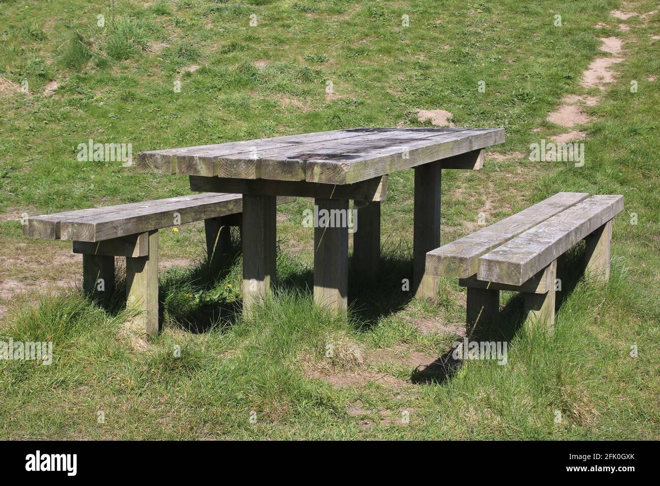 Gut gebrauchter, fester Holzpicknicktisch und zwei Holzbänke im Freizeitbereich Lane Ends, einem öffentlichen Bereich neben der Meeresmauer in Pilling, Lancashire. Stockfoto