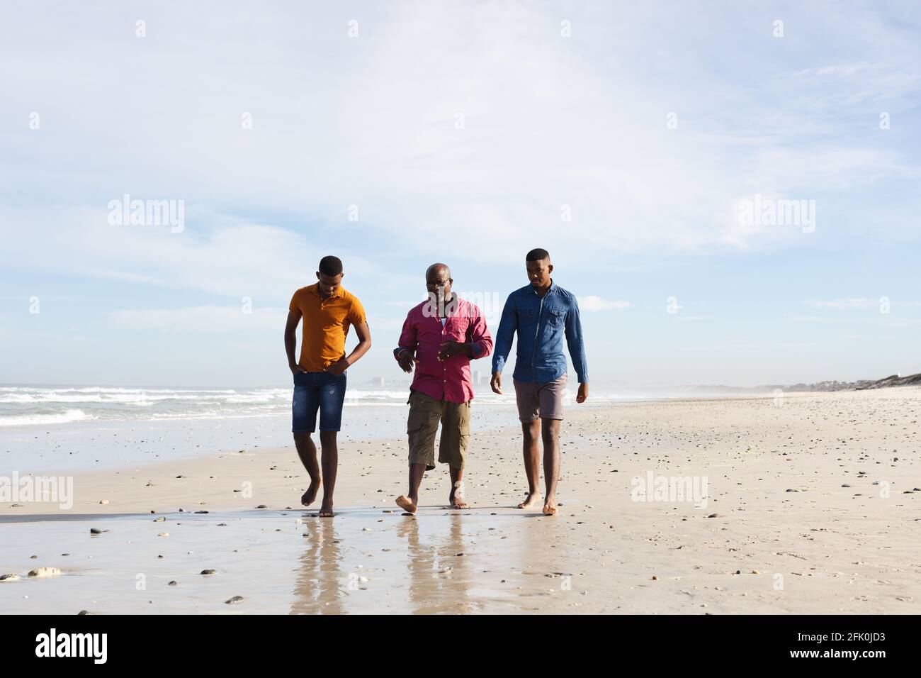 afroamerikanischer Vater und seine beiden Söhne gehen zusammen Der Strand Stockfoto