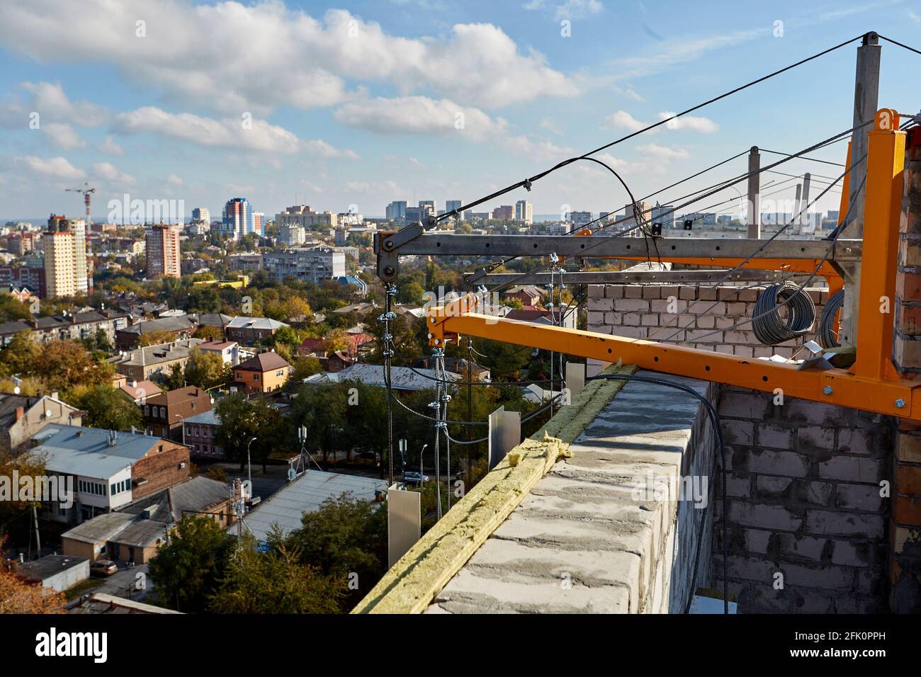 Malerischer Blick auf die Stadt vom Dach eines mehrstöckigen Gebäudes im Bau. Wiegekonsole vor blauem Himmel Stockfoto