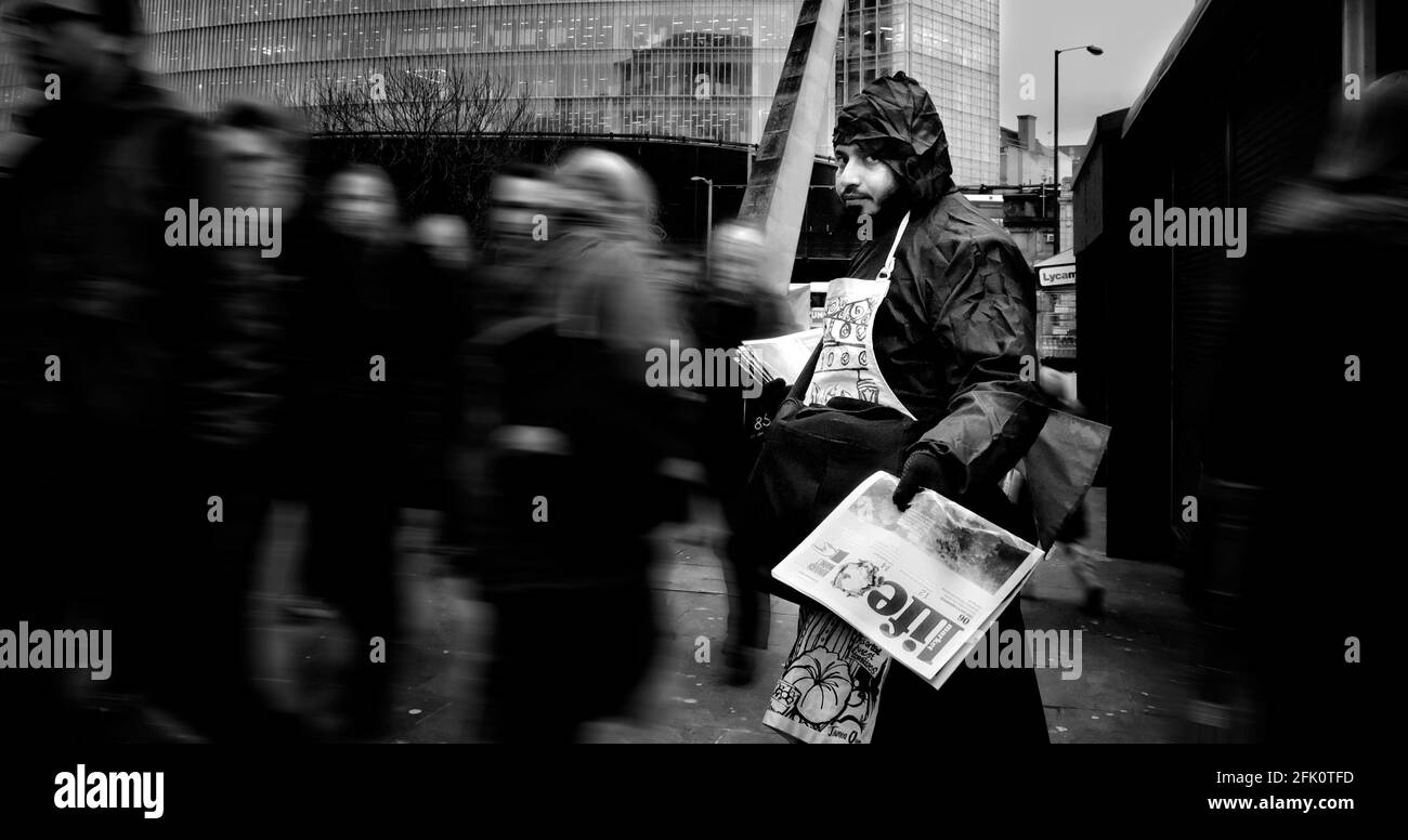 Ein Mann gibt kostenlose Zeitungen an vorbeifahrende Pendler in London Bridge, London, Großbritannien Stockfoto