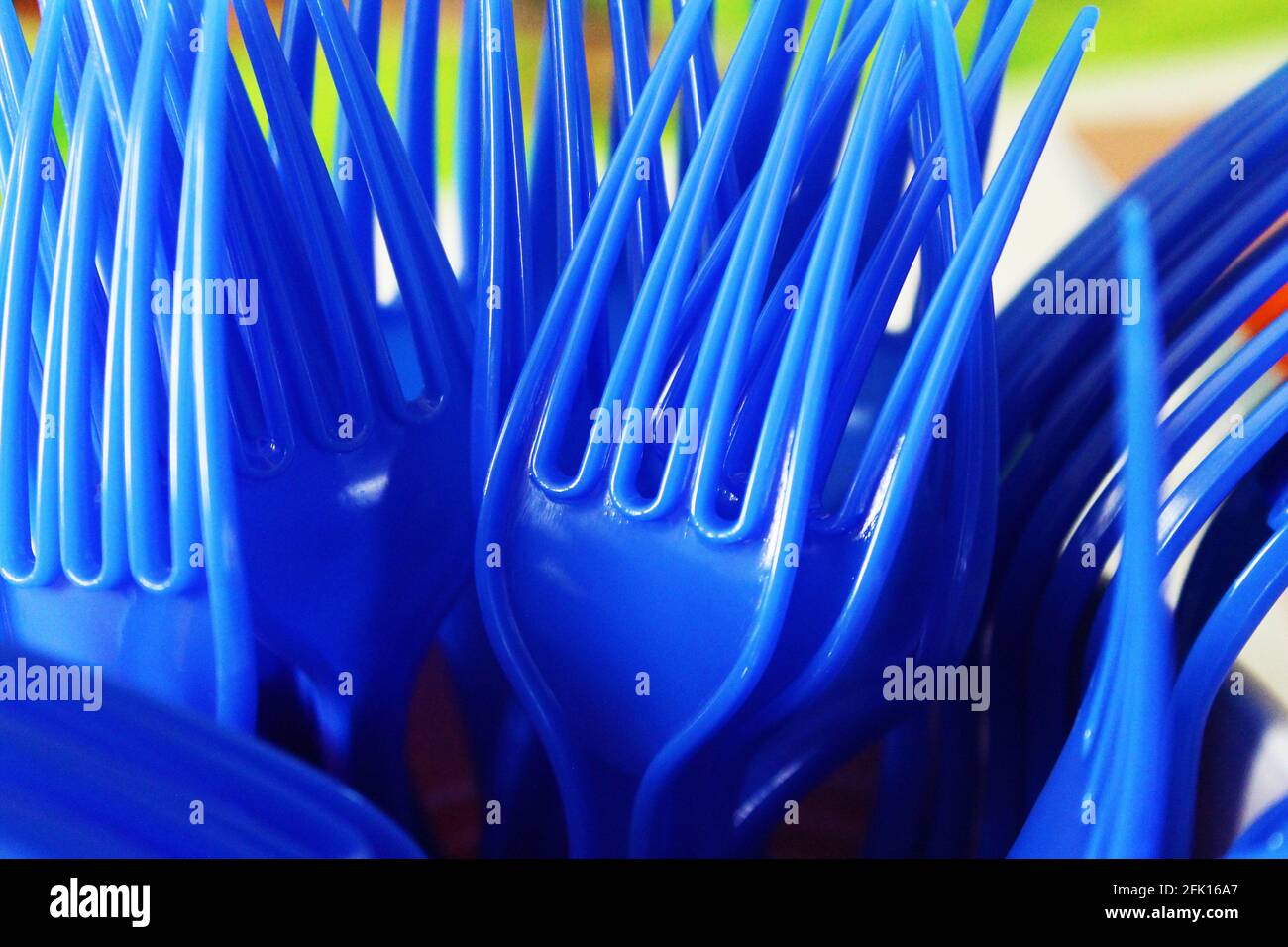 Nahaufnahme eines Bündels blauer Kunststoffgabeln stand in einem Plastikbecher auf, Zinken nach oben. Stockfoto