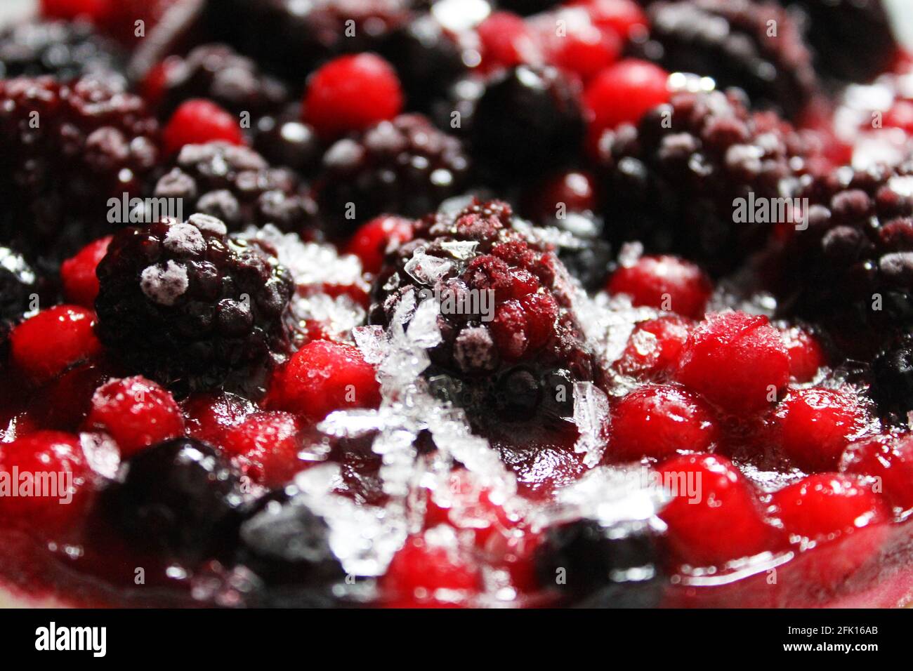 Nahaufnahme eines gefrorenen gemischten Beerenkäsekuchen mit einem leichten Eis und Frost auf den Beeren. Stockfoto