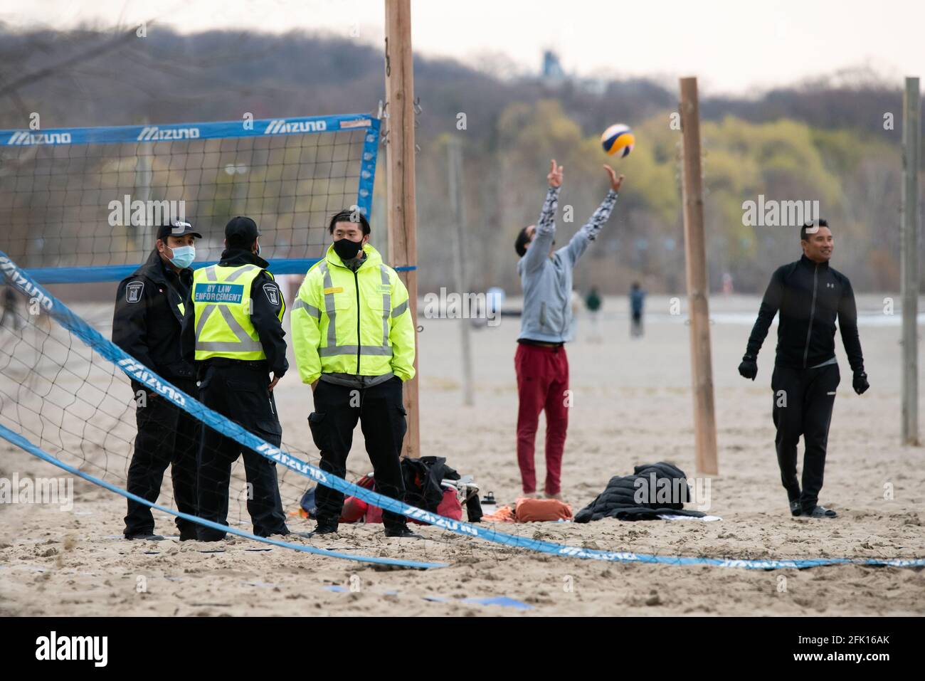 Durch die COVID-19-Sperre am Woodbine Beach in Toronto, Ontario, brechen per Gesetz am 27. April 2021 ein als illegal erachtete Volleyballspiel ab. Stockfoto