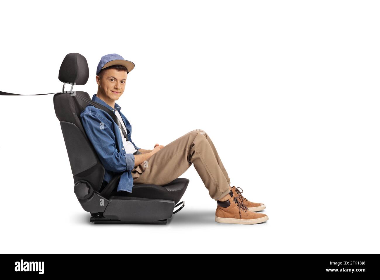 Männlicher Teenager, der mit einem Sicherheitsgurt auf einem Autositz sitzt Isoliert auf weißem Hintergrund Stockfoto