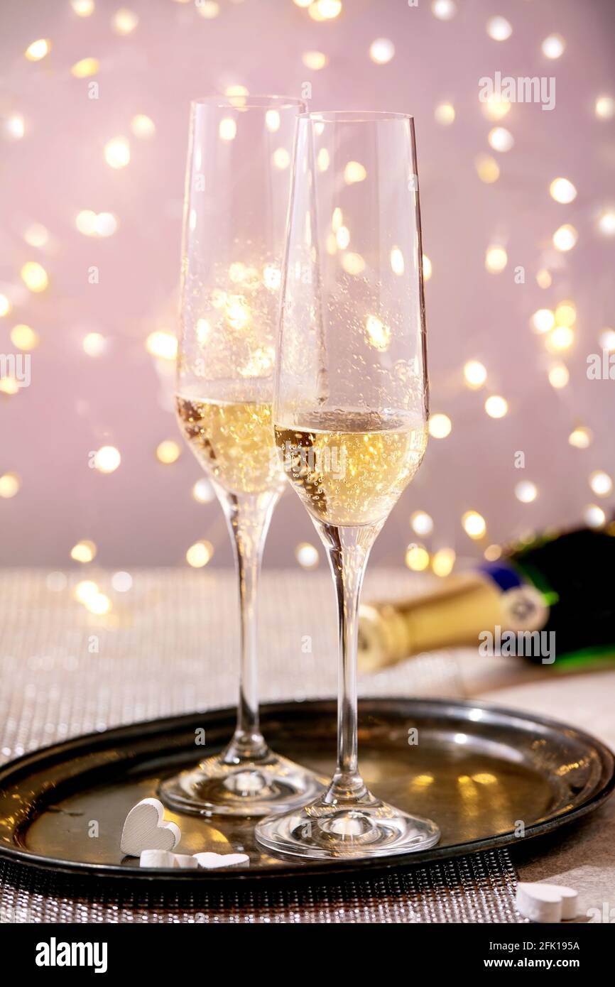 St. Valentine oder Hochzeit Grußkarte mit zwei Champagner Gläser auf Tablett stehen auf silbernen funkelnden Tisch, weiße Herzen, Bokeh Lichter. Festliche Tafel Stockfoto