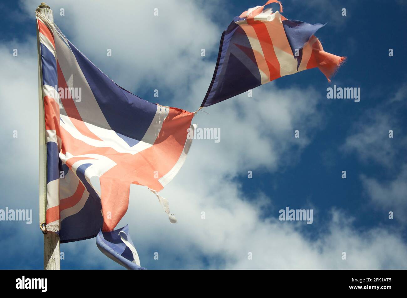 Alt und verblasst. Die Unionsflagge des Vereinigten Königreichs zerflattert und zerrissen, flattert und flattert im Wind gegen den Himmel. England, Großbritannien, Großbritannien. Stockfoto