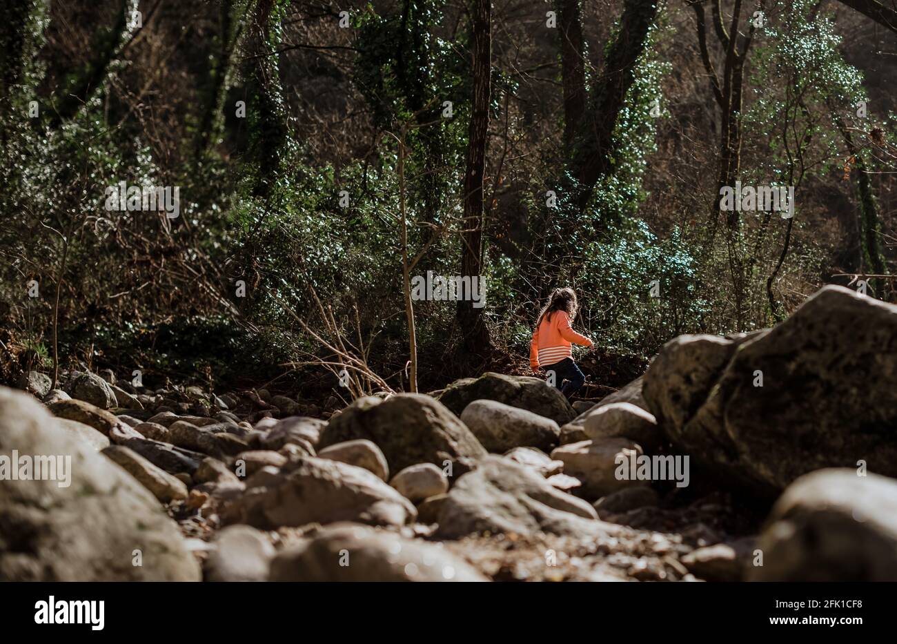 Mädchen geht durch riesige Felsen in Wäldern auf dem Land Stockfoto
