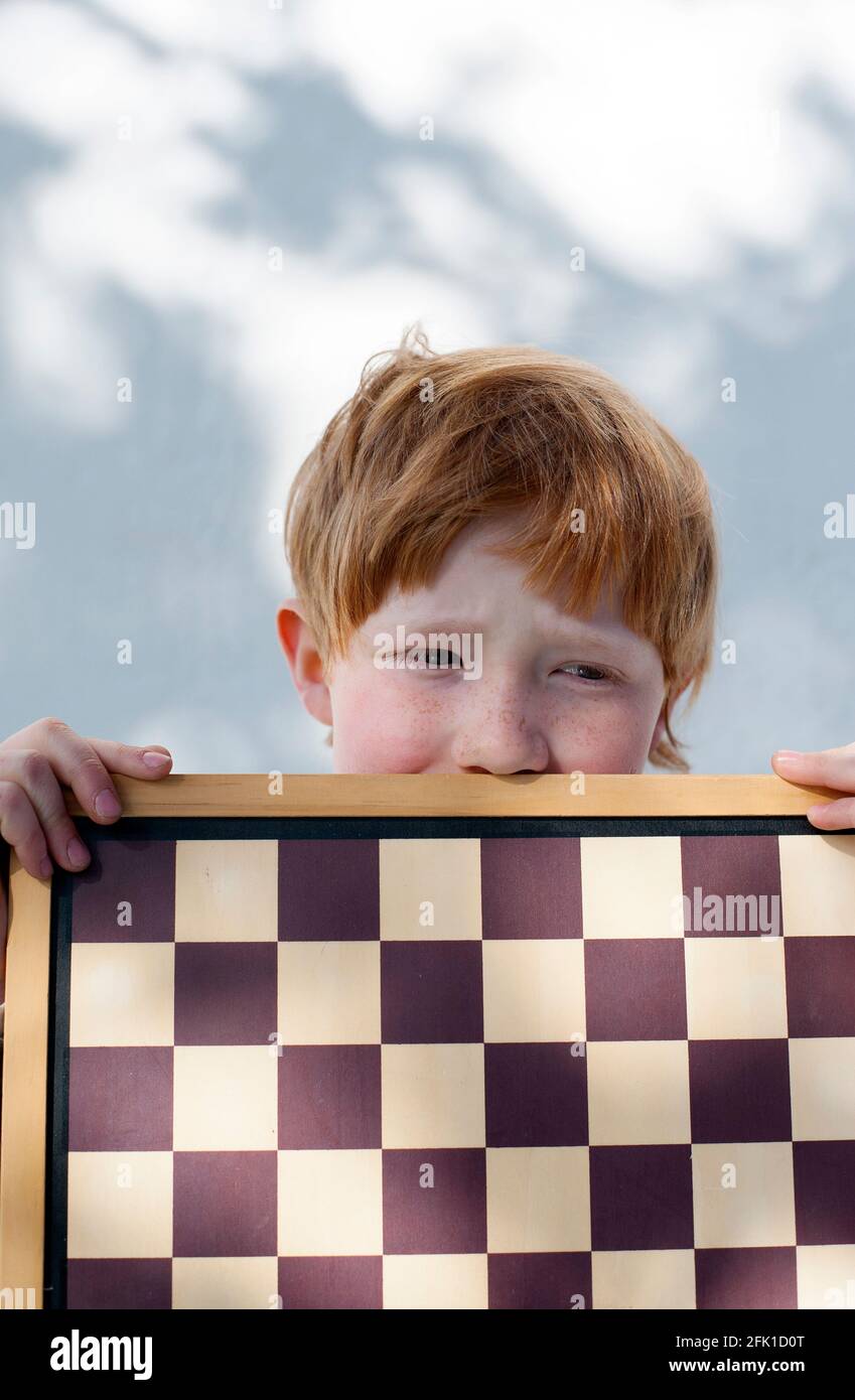 Kind mit roten Haaren spielt Schach Stockfoto