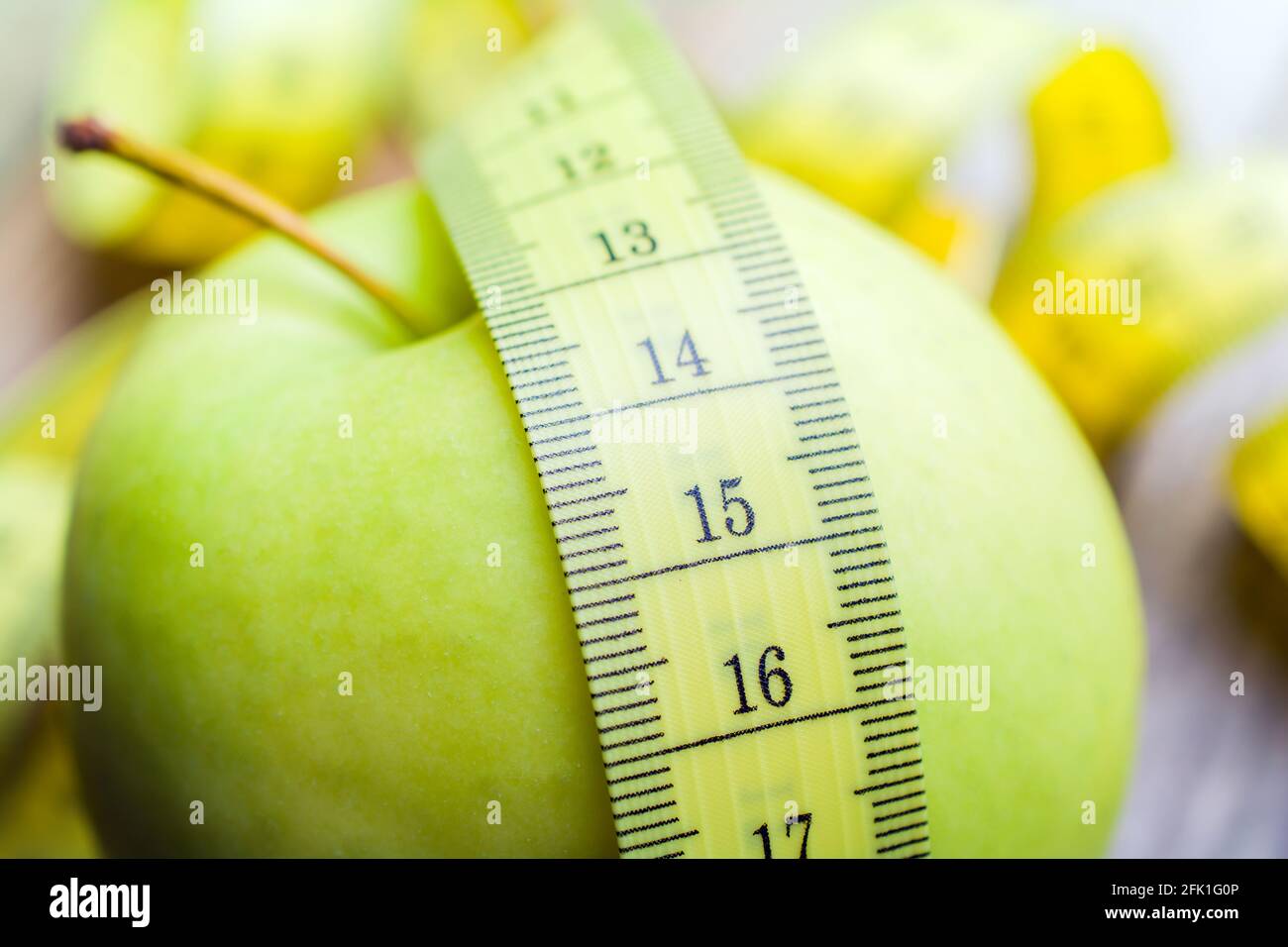 Gelbes Messband auf EINEM grünen Apfel liegend - Leben Gesundes Konzept Stockfoto