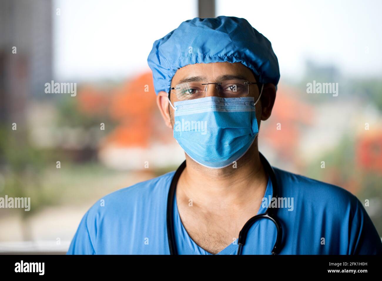 Selbstvertrauen junger männlicher Chirurg mit Gesichtsmaske, die die Kamera anschaut Stockfoto